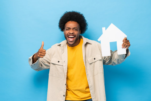 快乐的微笑非洲裔美国人持有的房子剪出孤立的浅蓝色工作室背景图片下载
