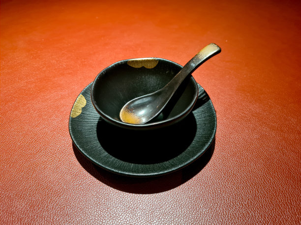 黑色的中国勺子和碗，金色图案的盘子:丰盛的中国菜肴在红色的皮革桌子上图片下载