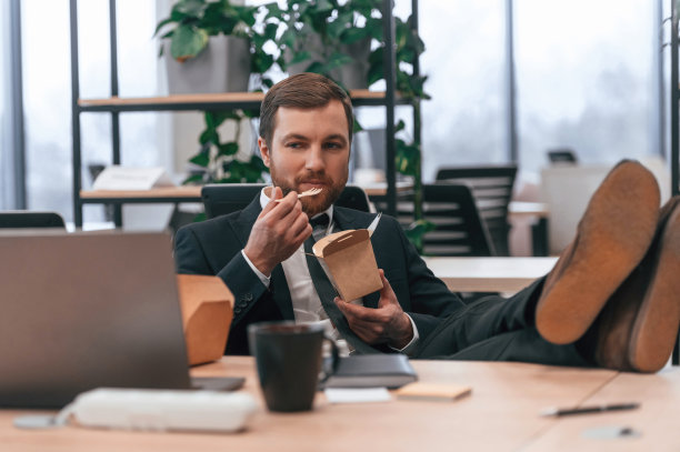 西装革履的商人在办公室吃着环保盒里的食物图片下载