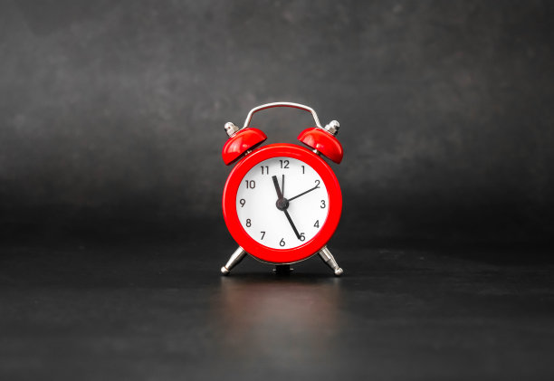红色铃铛闹钟在深黑色的背景与自然光线。提及个人护理时间表，提醒风湿病、关节病和迷路炎的药物和体育锻炼。图片下载