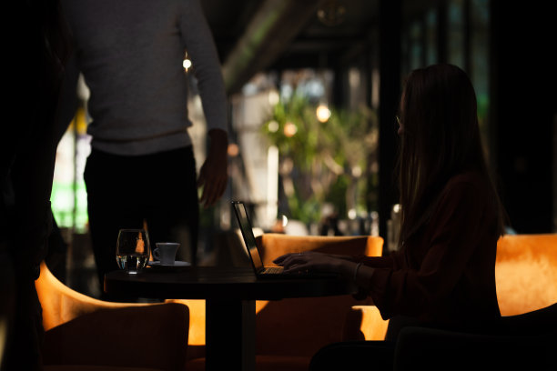 餐馆里的年轻女商人。自由职业者女孩剪影在咖啡馆的笔记本电脑上工作。图片下载