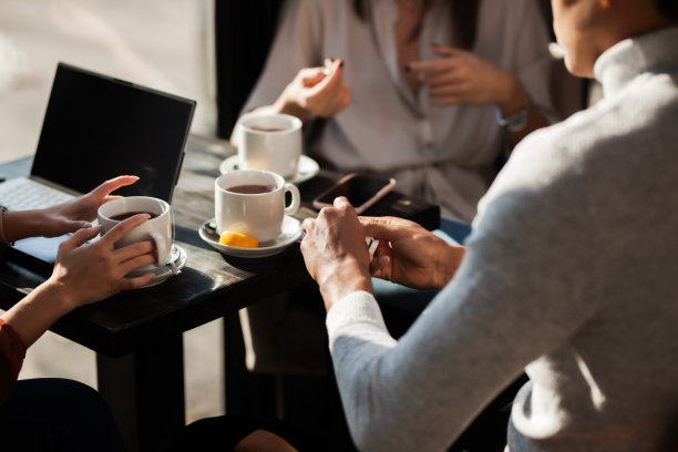 三个朋友在餐厅聊天喝茶。商务同事在下班后开会或在咖啡馆休息时。抽象照片聚焦茶杯。图片下载