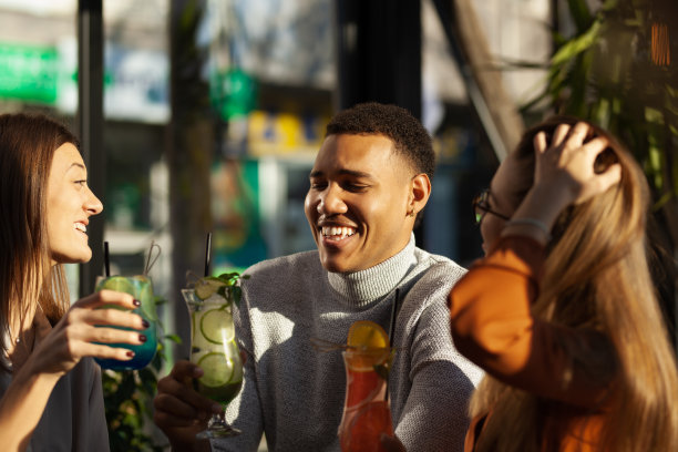 三个不同种族的朋友在酒吧里欢呼。工作结束后的鸡尾酒派对。图片下载