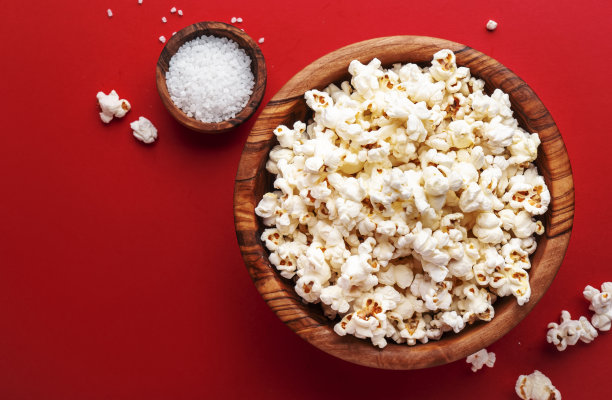 木碗里的咸爆米花，不健康的食物，鲜红色背景，俯视图图片下载