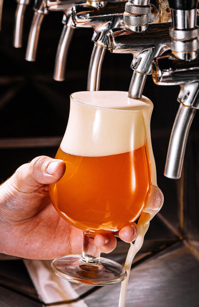 酒吧里的酒保把新鲜的啤酒倒进玻璃杯里图片下载