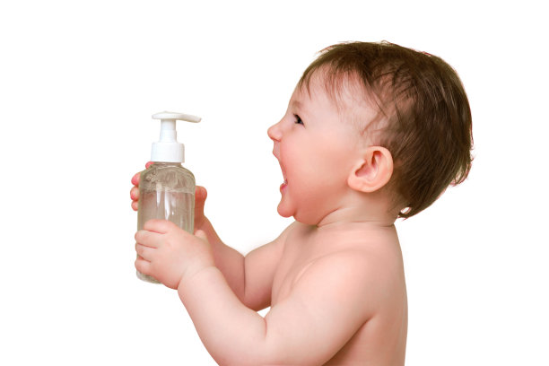 快乐的婴儿蹒跚学步的男孩与液体肥皂在浴缸里，孤立的白色背景。一岁时微笑的孩子图片下载