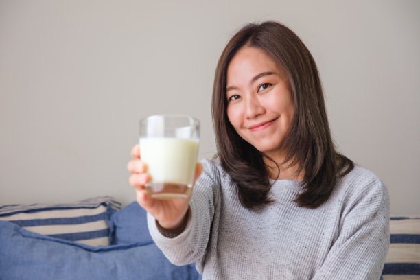 一个年轻女子拿着一杯新鲜牛奶的肖像图像图片下载
