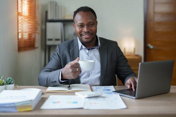 中年男子美国非洲人使用笔记本电脑与计划工作的财务文件，税务，外汇，会计和财务顾问图片下载