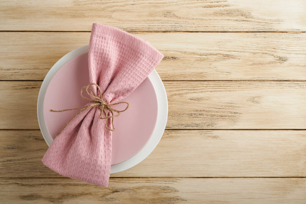 复活节早午餐餐桌摆设。春季复活节假期概念与白色，粉红色的盘子和餐巾装饰符号节日兔子，鸡蛋和花束在旧的木制背景。前视图。图片下载