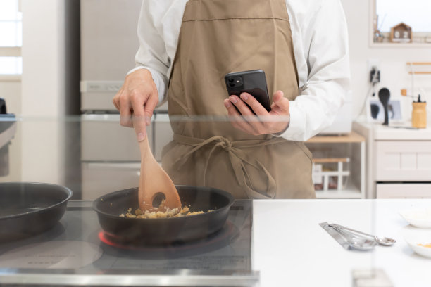 40多岁的男人在厨房用智能手机做饭图片下载