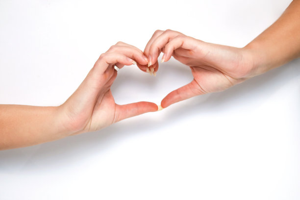 女人用她的手指在白色背景上做一个心形的手势。象征着爱、和谐、感恩、慈善。爱情生活。白色背景上的手的心形图片下载