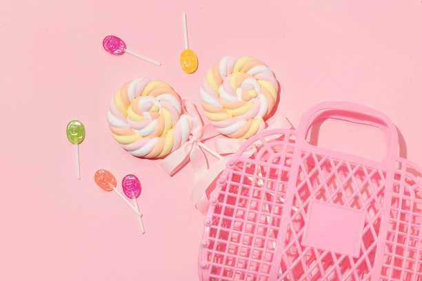 夏季创意布局粉红色果冻篮和棒棒糖粉彩粉红色背景。八九十年代复古时尚审美爱糖果概念。极简浪漫的化妆理念。图片下载