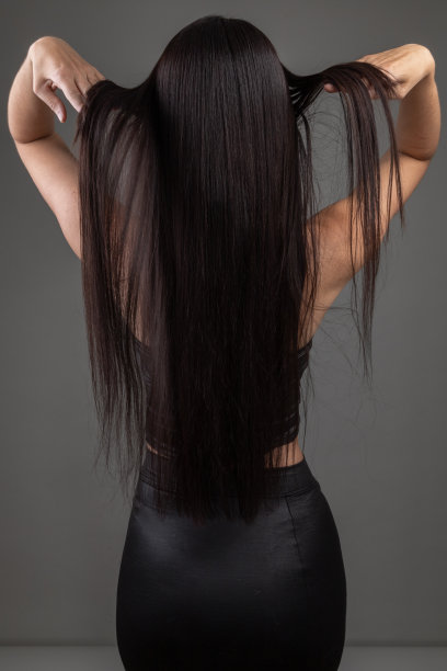 长，黑色，直发的年轻女子从后面，剪影的人在工作室图片下载