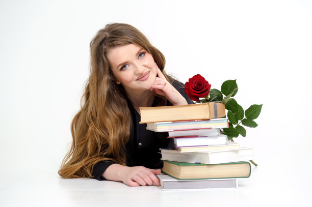 大学女老师躺在课本上，手里拿着玫瑰，性感的老师老师穿着高跟鞋，黑色衣服，飘逸的头发，白色背景上的文字红玫瑰培训来吧图片下载