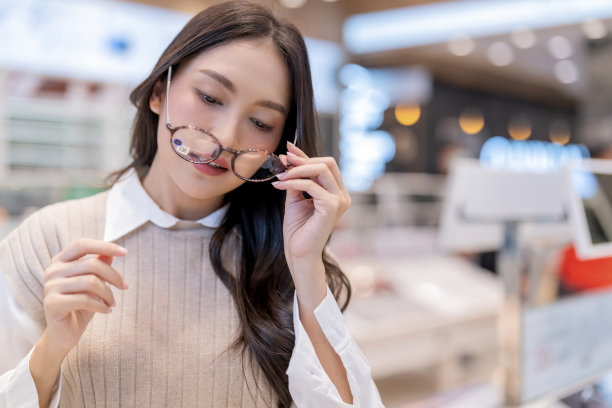 迷人的亚洲年轻成年女性女性休闲布度过周末假期享受选择眼镜在光学商店商店，她是为自己挑选最喜欢的一个图片下载