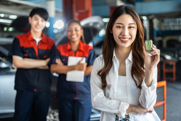 领取车钥匙的女人。穿着制服的年轻汽车修理工工程师正在把车钥匙还给客户，两个人都面带微笑。图片下载