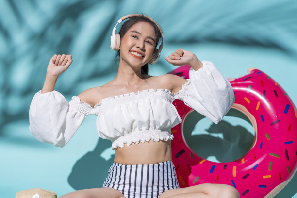 快乐开朗的亚洲青少年女子放松休闲在夏季连衣裙听音乐耳机，同时随着旋律跳舞，女子坐幸福与充气夏季概念工作室拍摄图片下载