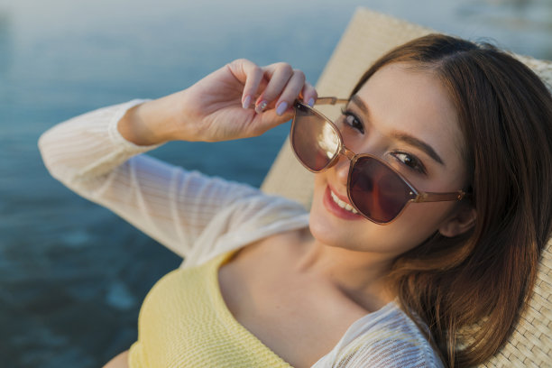 放松夏天休闲休闲亚洲女性女性在泳装上凉爽的藤条泳池长椅上躺在游泳池附近，无边泳池边在建筑物的屋顶上，夏天旅游度假日光浴图片下载