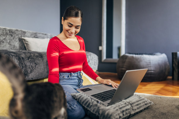一位年轻女子一边和她的猫玩耍，一边在家工作图片下载