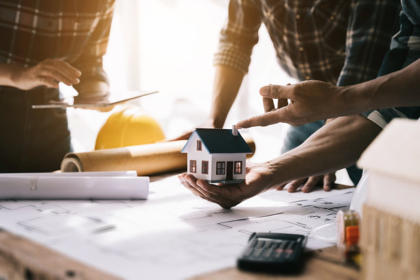 两个同事在办公室的办公桌上讨论数据工作和平板电脑，笔记本电脑和建筑项目。图片下载