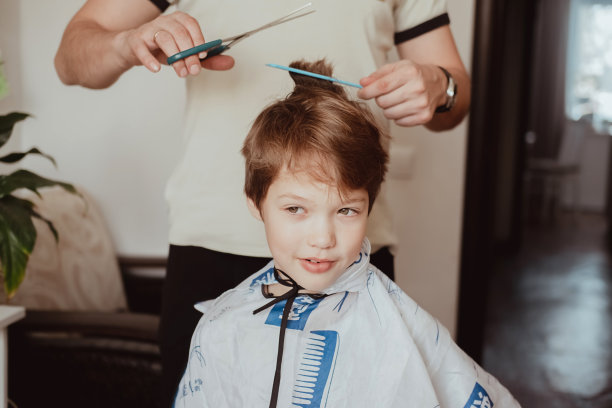 在隔离条件下的美发沙龙。父亲用剪刀给儿子剪头发。男人在家里给男孩理发。经济危机中的经济概念。图片下载