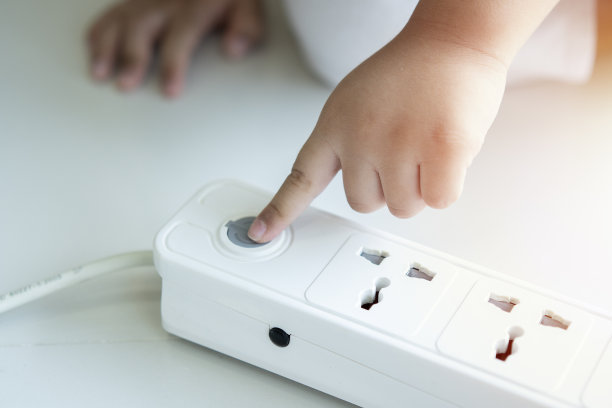 小孩在玩电源插座。在家触电的危险。插座上的儿童插头。图片下载