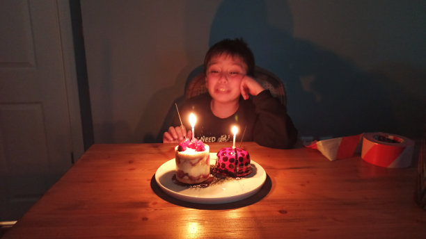 哭着的男孩在吹生日蛋糕上的蜡烛前许了个愿图片下载