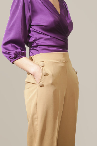 系列工作室的照片，年轻的女模特穿着紫罗兰色的丝绸缎包裹衬衫和米色的高腰裤图片下载