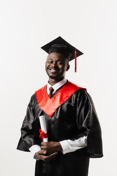 自信的非洲男子学士毕业长袍和帽子上的白色背景。快乐和有趣的非洲毕业生男子微笑。学生在大学取得硕士学位，图片下载