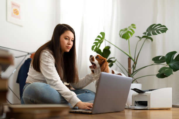 年轻的女人在家里的地板上工作，还有可爱的狗图片下载