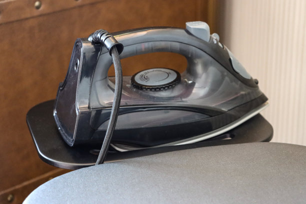 熨衣板托盘上的熨斗特写图像，银色熨衣板封面，重点在前景图片下载
