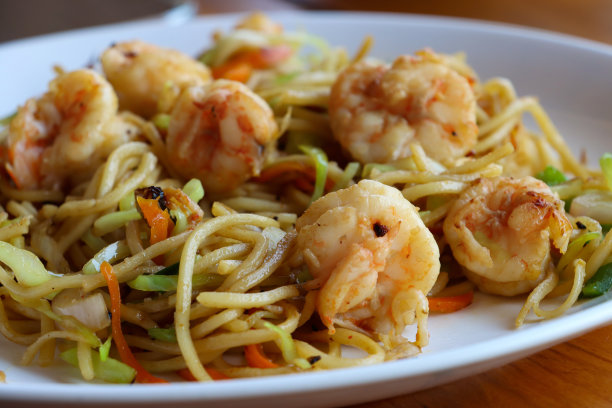 白色盘子的特写图片，里面有虾面和什锦炒菜，中餐外卖，切碎的青椒，切片的胡萝卜和洋葱，重点在前景图片下载