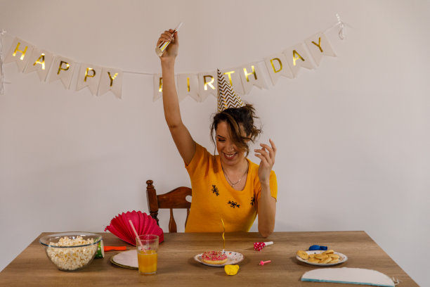 快乐的年轻女子有乐趣在一个单独的生日庆祝活动图片下载