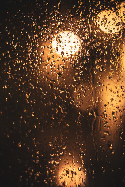湿漉漉的玻璃上沾着水滴，对着发光的灯光图片下载