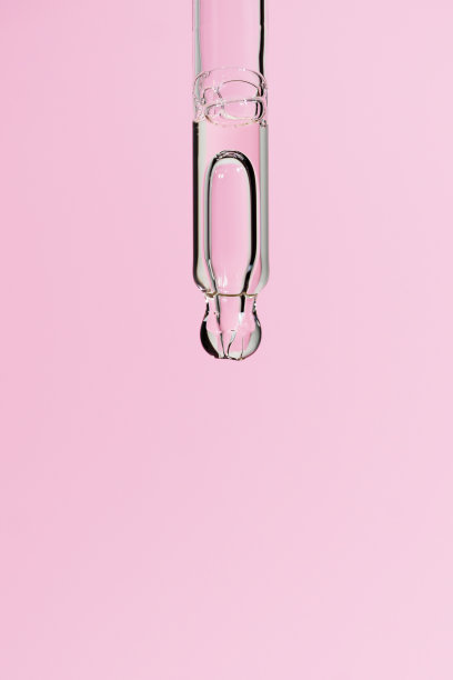 淡粉色背景上有大气泡的玻璃移液管中的血清。液体凝胶或精油与气泡宏。含有视黄醇或胶原蛋白的时尚化妆品。复制空间，前视图图片下载