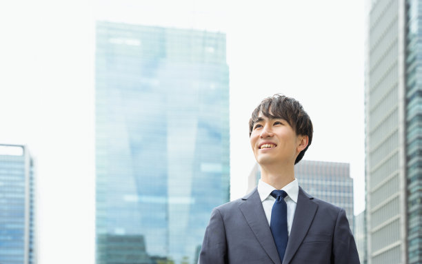 在城市的户外，20多岁、30多岁的西装革履的男人微笑着看着远方图片下载