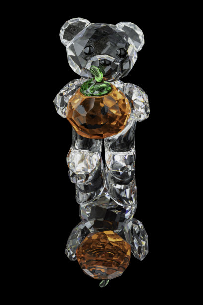 万圣节那天，水晶熊正拿着一个南瓜，黑色背景上有反射阴影。图片下载