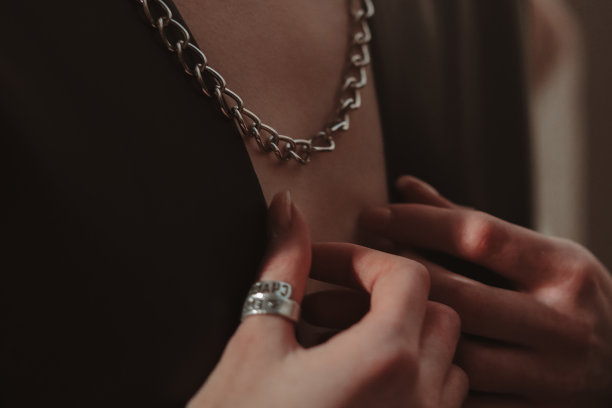 女性的手，银链挂在脖子上的女人穿着一件黑色夹克。图片下载