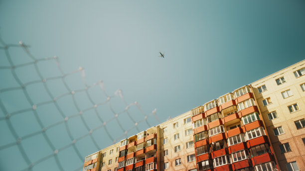 在晴空万里的晴天，商业飞机飞过东欧城市的郊区。飞往国际目的地的现代客机。来自地面的镜头。图片下载