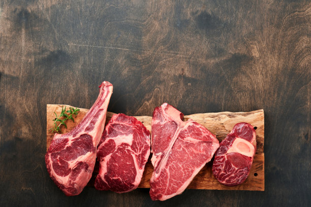 生牛排。各种新鲜的黑安格斯优质肉牛排t骨，纽约，Ribeye, Striploin，战斧砧板上的黑色或深色背景。各种经典牛排。前视图。图片下载