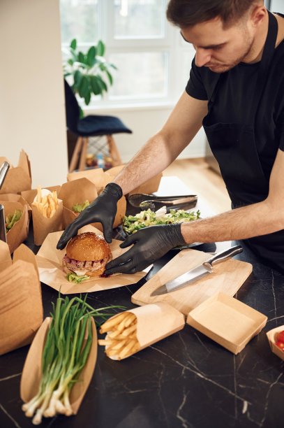 汉堡在手。一个人正在把食物装进环保纸盒里。在室内,餐厅图片下载