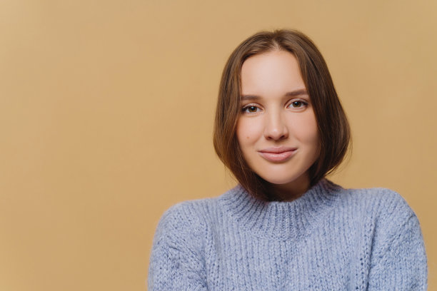 头部有吸引力的女人长发，迷人的样子，穿着紫色针织毛衣，直视镜头，模特在棕色背景，左侧空白。人,温柔图片下载