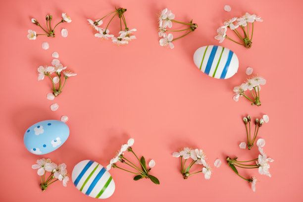 白色的花、樱花和粉色背景上有蓝色条纹的复活节彩蛋。复活节背景，复制空间。Flatlay。图片下载
