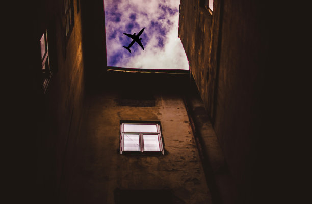 透过房子的庭院，可以看到空中飞行的飞机图片下载