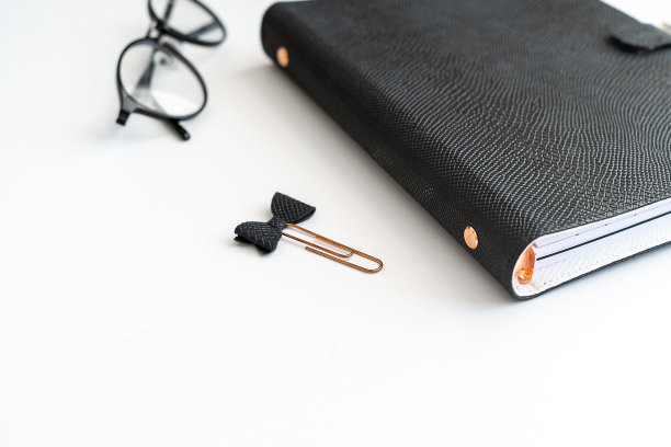 靠近图片的黑色记事本在白色的桌子与眼镜一边。模型空白空间复制空间黑色笔记本计划日志图片下载