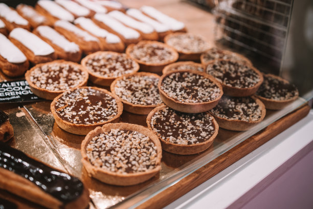 一个展示柜装满了许多不同类型的蛋糕和派展示在面包店或熟食店或面包店的蛋糕和糖霜在货架上的正面视图。图片下载