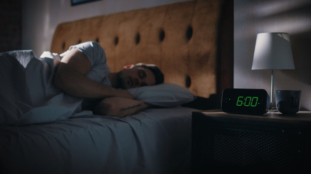 男人醒来，关掉闹钟。早起的富有成效的人准备开始一天的业务项目。把注意力集中在六点钟的时钟上。电影。床头柜图片下载