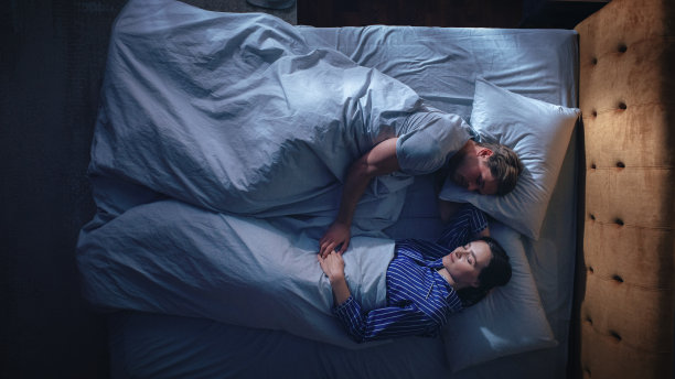 俯视图公寓:幸福的年轻夫妇睡在床上的夜晚。美丽的女朋友和英俊的男朋友睡在一起。两口之家甜蜜地面对面睡觉。从上到下图片下载