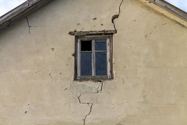 房子正面有裂缝。房子阁楼上的窗户有半腐烂的木框图片下载