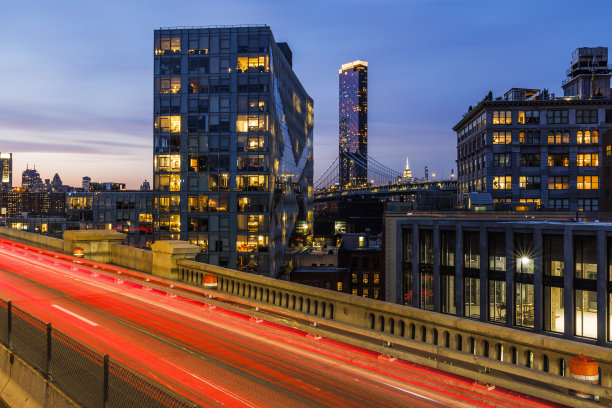 夜晚灯火通明的布鲁克林大桥，可以看到布鲁克林的现代建筑。模糊的运动效果。图片下载
